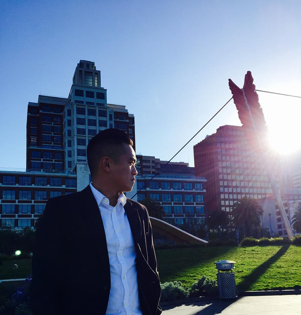 Andrew Ngin standing in front of city skyline at sunset